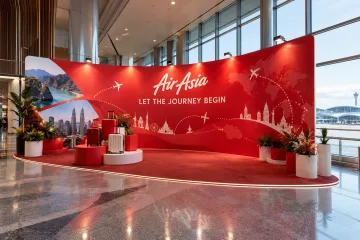 AirAsia travel campaign launch with curved launch wall, abstract travel-route graphic and luggage display plinths