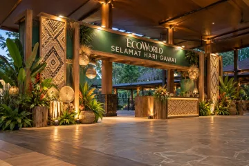 EcoWorld gawai celebration with a wide walk-through community entrance gateway with timber-look frame, Sarawak-inspired woven texture panels, tasteful harvest decorations and welcome counter